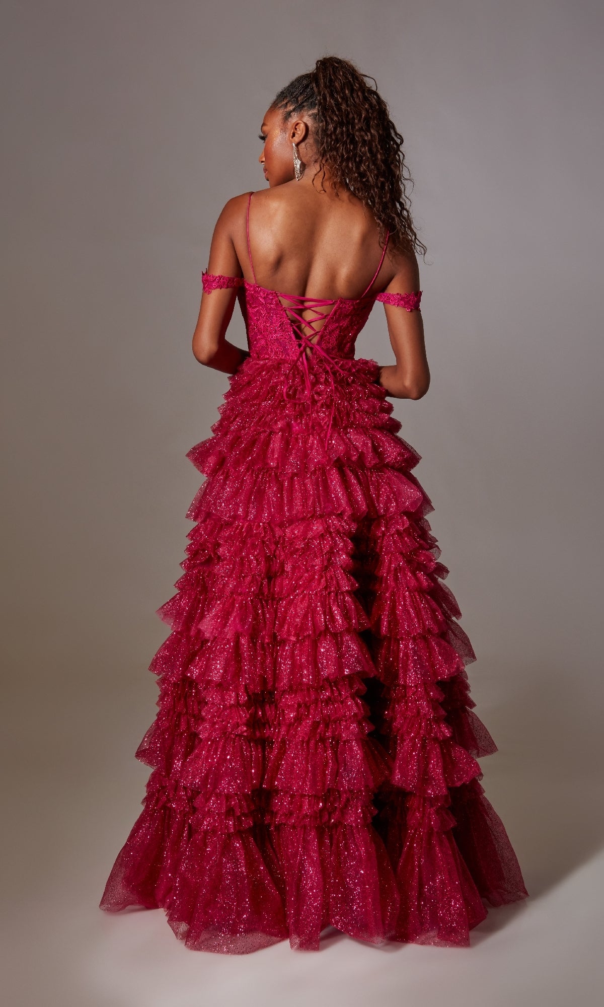 A woman faces away from the camera, wearing the Raspberry Pink Long Glitter Prom Dress with ruffles, featuring spaghetti straps and off-shoulder sleeves.